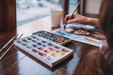 High angle view of young woman painting at cafe - FSIF03053