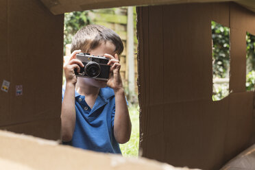 Junge fotografiert durch ein Spielhaus aus Pappe im Hinterhof - FSIF03072