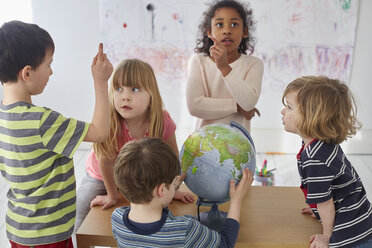 Kinder diskutieren bei der Erforschung des Globus am Tisch in der Vorschule - FSIF03082