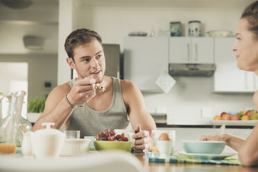 Junges Paar isst Obst zum Frühstück am Küchentisch - ISF08892