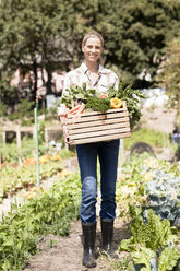 Porträt einer reifen Frau im Garten, die eine Kiste mit frischem Gemüse hält - ISF08915