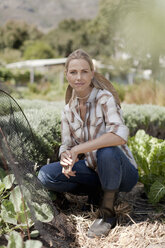 Portrait of mature woman crouching in garden - ISF08918