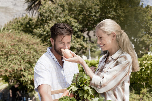 Älteres Paar im Garten, Frau hält frische Zwiebel hoch, damit der Mann daran riechen kann - ISF08931