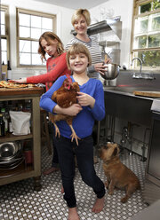 Mutter und Töchter in der Küche bereiten eine Mappe vor, die jüngere Tochter hält ein Huhn - ISF08944