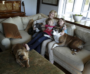 Mutter und Töchter sitzen auf dem Sofa mit Haustieren Hunde, Fernsehen zusammen - ISF08945