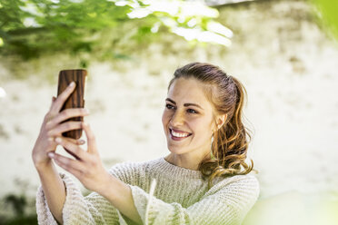 Porträt einer entspannten Frau, die ein Selfie mit ihrem Mobiltelefon macht - FMKF05076