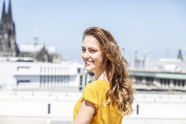 Germany, Cologne, portrait of smiling woman on roof terrace - FMKF05105