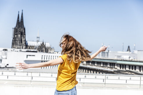 Germany, Cologne, woman dancing on roof terrrace - FMKF05106