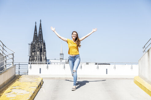 Deutschland, Köln, glückliche Frau auf der Rampe eines Parkhauses mit dem Kölner Dom im Hintergrund - FMKF05120