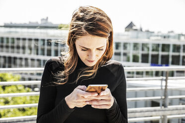 Woman text messaging on roof terrace - FMKF05122