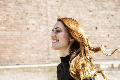 Portrait of smiling woman with blowing hair - FMKF05124