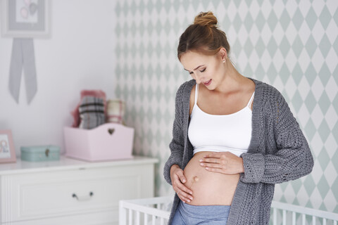 Schwangere Frau streichelt Babybauch, lizenzfreies Stockfoto