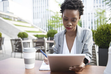 Portrait of businesswoman using digital tablet at sidewalk cafe - ABIF00535