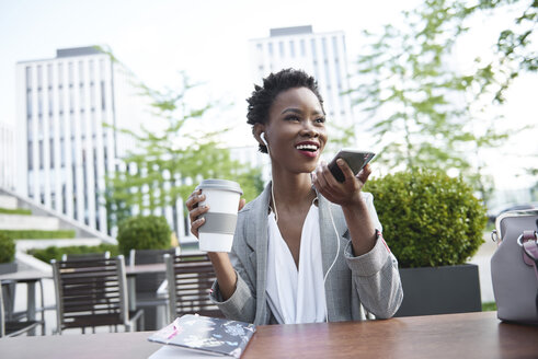 Portrait of smiling businesswoman on the phone at sidewalk cafe - ABIF00540