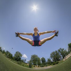 Sportliche junge Frau, die in die Luft springt, spagat, fisheye - STSF01593