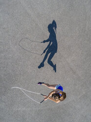 Aerial view of young woman skipping rope, shadow - STSF01597