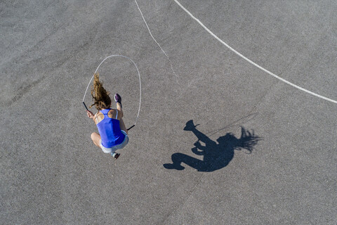 Luftaufnahme einer jungen Frau, die Seil springt, Schatten, lizenzfreies Stockfoto