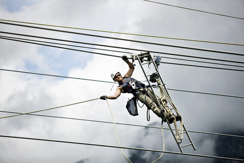 Fitter with ladder, pulling along high-voltage power line - CVF00695