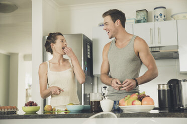 Junges Paar isst Obst bei der Zubereitung des Frühstücks am Küchentisch - ISF09032