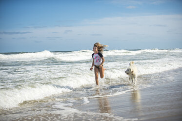 Young girl running through sea with dog - ISF09075