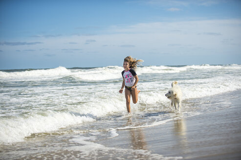 Junges Mädchen läuft mit Hund durchs Meer - ISF09075