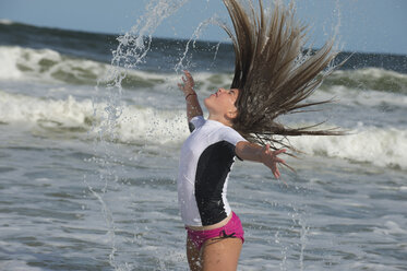 Junges Mädchen steht im Meer und streicht sich über die nassen Haare - ISF09077