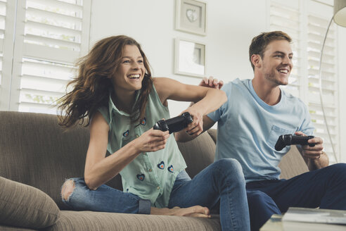 Ehepaar auf Sofa mit Videospiel-Controller lächelnd - ISF09086
