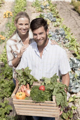 Porträt eines reifen Paares im Garten, das eine Kiste mit frischem Gemüse hält - ISF09096