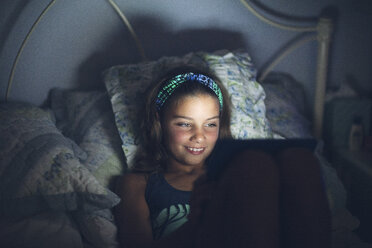 Girls in bed using digital tablet smiling - ISF09100