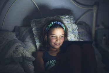 Mädchen im Bett mit digitalem Tablet lächelnd - ISF09100