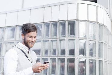 Mature man walking outdoors, using smartphone - ISF09108