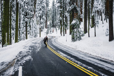 Skateboarder auf der Straße in einer Winterlandschaft, Sequoia National Park, Kalifornien, USA - ISF09130