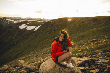 Frau sitzt auf einem Felsen und schaut lächelnd in die Kamera, Rocky Mountain National Park, Colorado, USA - ISF09141