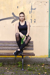 Sportliche Frau mit Wasserflasche auf einer Bank sitzend - MMIF00116