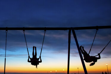 Kinder spielen auf einer Schaukel bei Sonnenuntergang, Seaside Park, New Jersey, USA - ISF09180