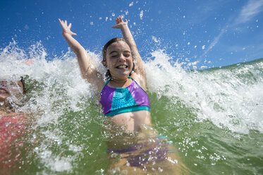 Girls jumping with joy in ocean wave - ISF09189