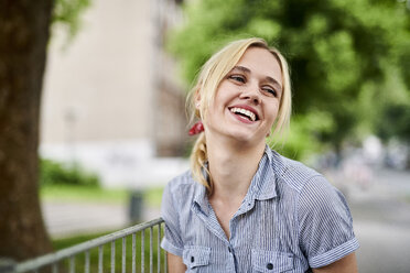 Laughing blond young woman at a fence - MMIF00150