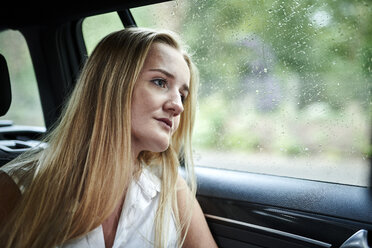 Ernste blonde junge Frau in einem Auto an einem regnerischen Tag - MMIF00155