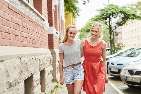Zwei glückliche junge Frauen gehen zusammen durch die Stadt - MMIF00162
