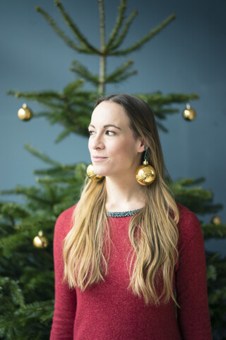 Porträt einer Frau mit goldenen Weihnachtskugel-Ohrringen, lizenzfreies Stockfoto