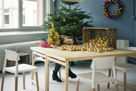 Woman sitting at table with many golden Christmas baubles stock photo