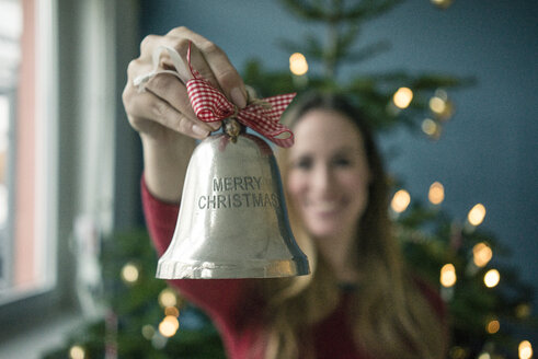 Woman's hand holding silver Christmas bell - MOEF01364