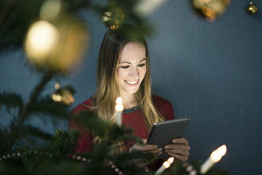 Porträt einer lächelnden Frau, die zur Weihnachtszeit ein Tablet benutzt - MOEF01371