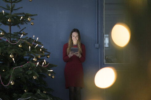 Lächelnde Frau in einem Loft mit Tablet zur Weihnachtszeit - MOEF01372