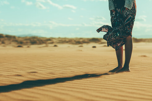 Legs of young woman standing in sand dune - OCAF00261