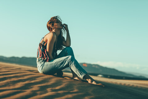 Young woman sitting in desert landscape stock photo