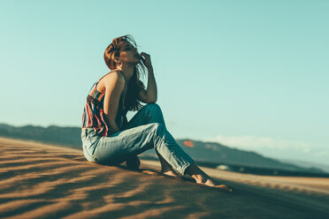 Young woman sitting in desert landscape - OCAF00272