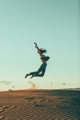 Junge Frau springt in Wüstenlandschaft - OCAF00276