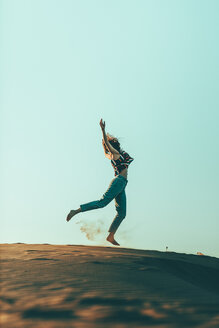 Junge Frau springt in Wüstenlandschaft - OCAF00277