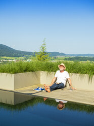 Senior man sitting at swimming pool - LAF02054